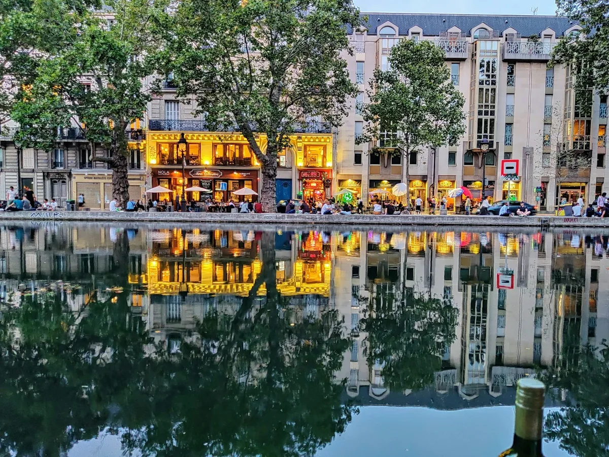 Evening lights and buildings reflected in Canal Saint-Martin along Quai de Valmy, Paris